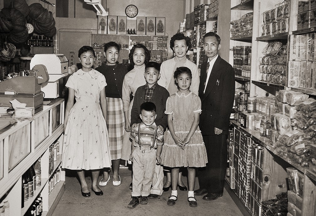Sepia photo of family standing in a Chinatown shop.