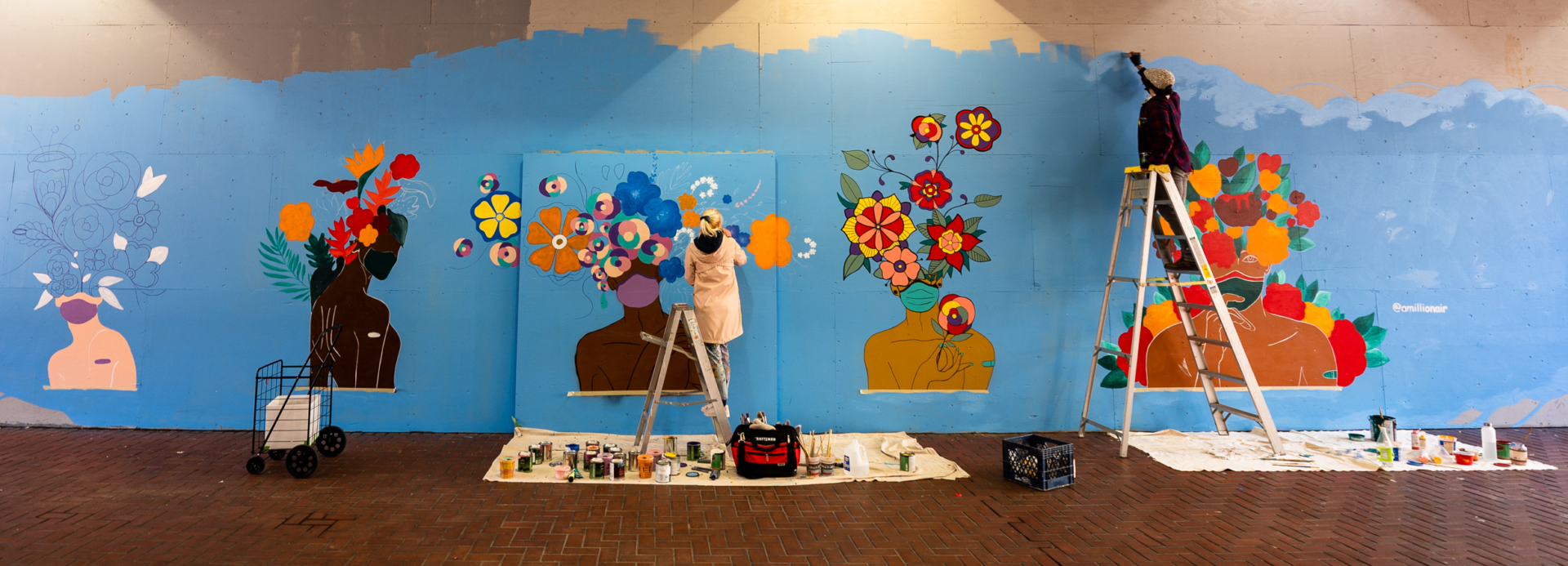 Amillionair paints a mural in collaboration with street artist Seibot outside the Powell Street BART Station