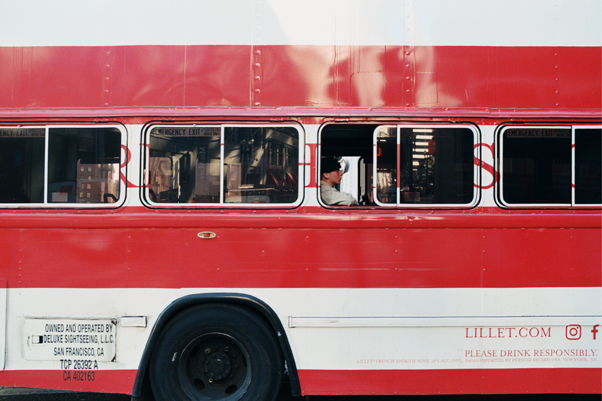 Photograph of a red and white bus with a man staring forward in one of the windows
