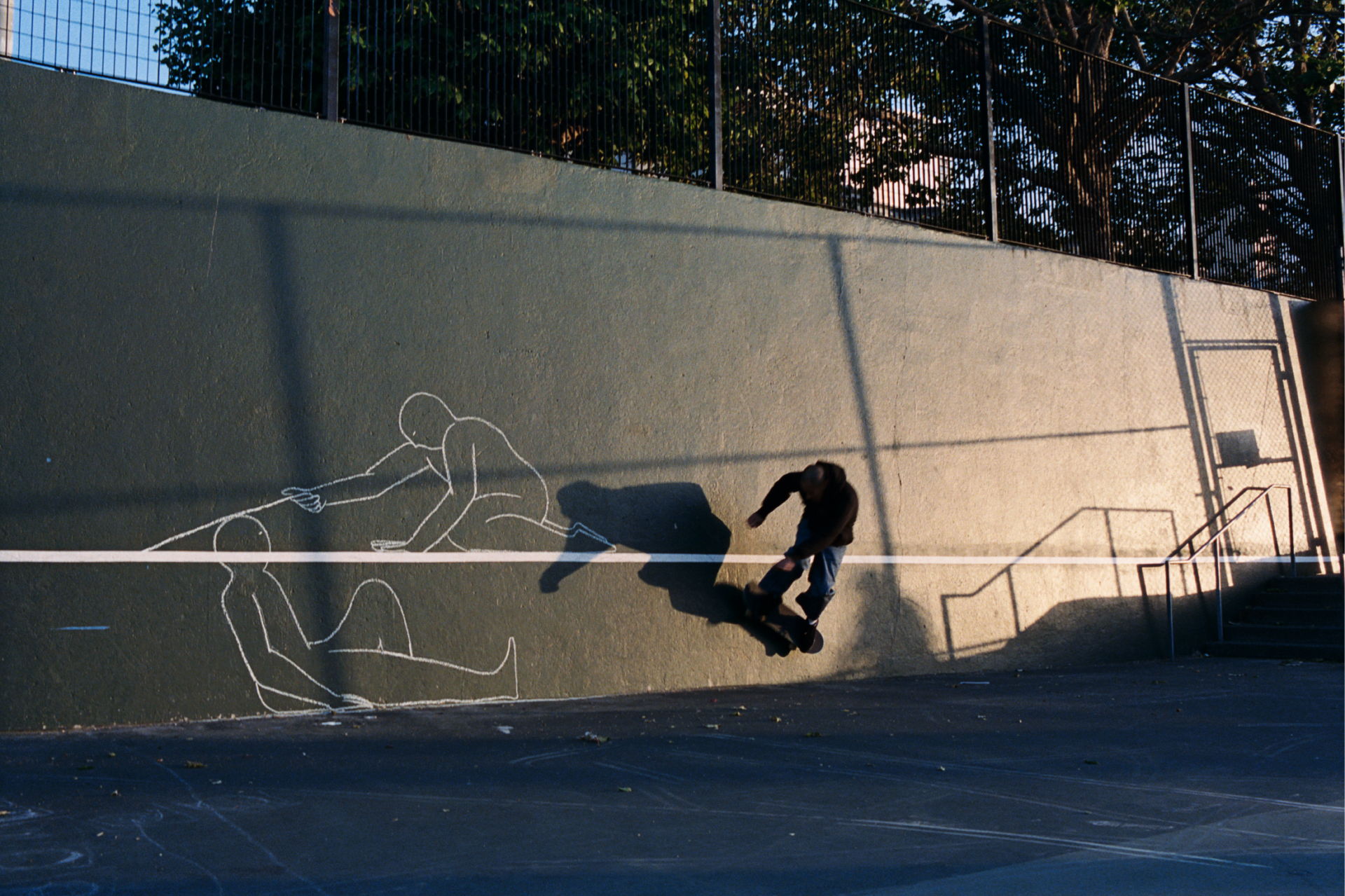 Photograph of skateboader Martin riding next to a chalk art illustration he made at the Joe DiMaggio Playground in North Beach