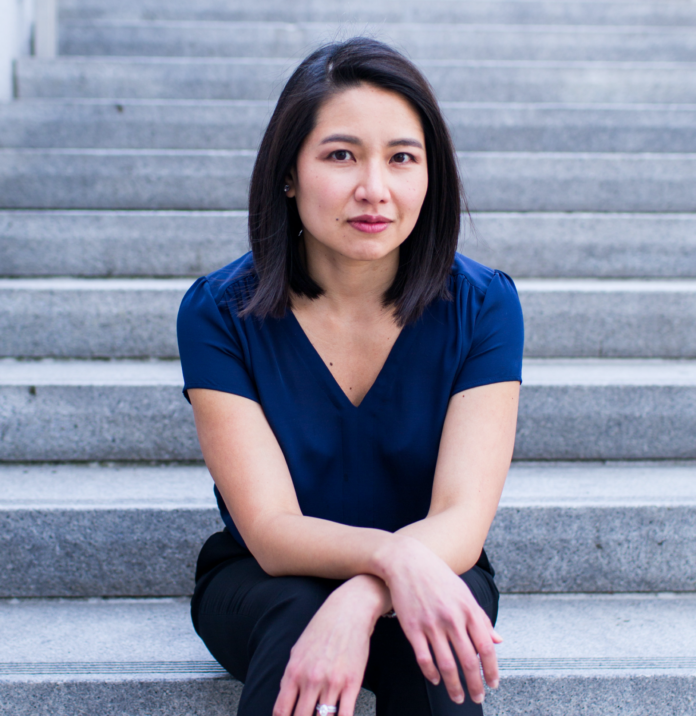 Portrait of author Kirstin Chen sitting on concrete steps