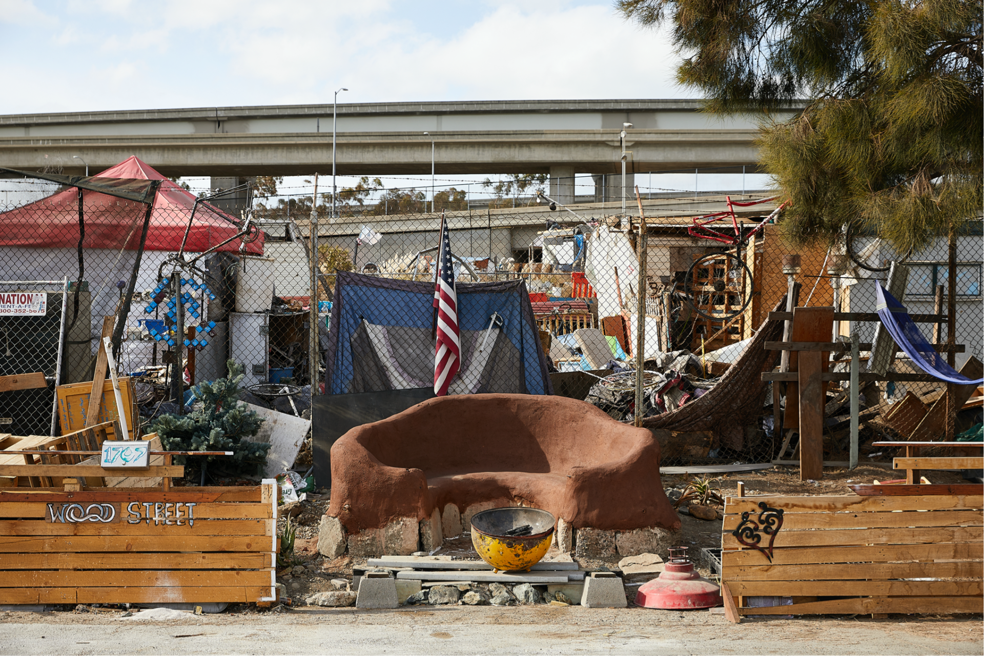 A photograph of the Wood Street encampments, which are surrounded by illegally dumped garbage from across Oakland