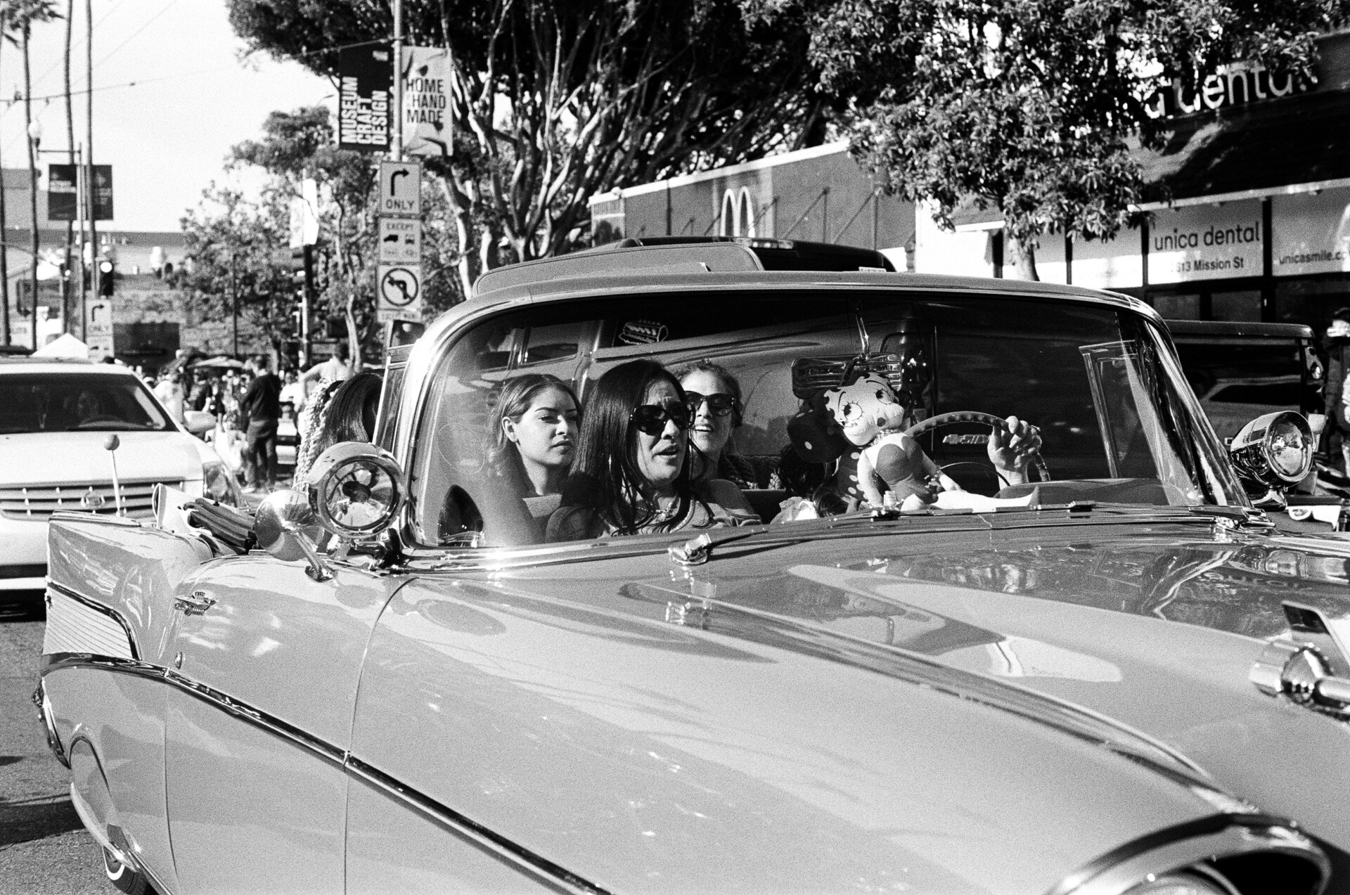 Three women cruise down Mission Street in their lowrider car.