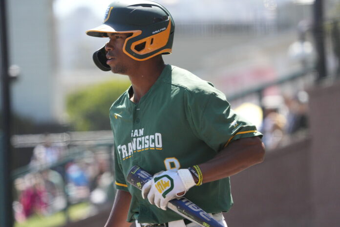 Darius Foster, helmet on and bat in hand, walks out onto the field.